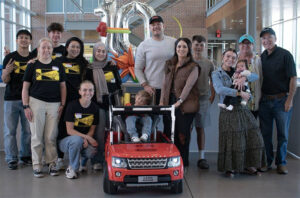 Members of the GoBabyGo team pose with a family and they modified a children's car for