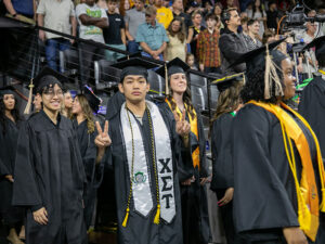 A student gives the peace sign with his hands at a commencement ceremony at Wichita State