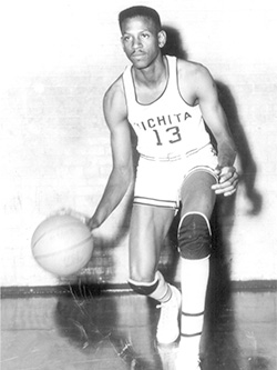 Cleo Littleton in his University of Wichita gear dribbles a basketball on a court