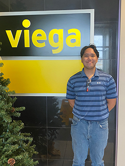 Isiah Tiongson stands beside a Viega company sign.