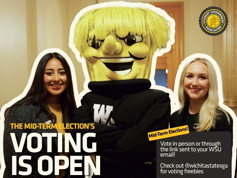 Promotional graphic for the Wichita State University Student Government Association Mid-Term Elections. The image features two students standing on either side of WuShock, the university mascot, in a campus building. Large text reads, “The Mid-Term Election’s Voting Is Open.” Additional text encourages students to vote in person or through the link sent to their WSU email and to visit @wichitastatesga for voting freebies. The Student Government Association logo appears in the upper-right corner.