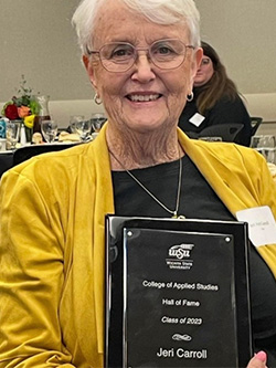 Jeri Carroll holds up her College of Applied Studies Hall of Fame plaque