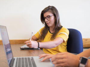 A student takes a proctored exam at a desk
