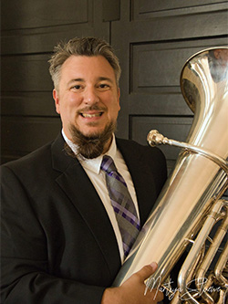 Faculty soloist Lucas Hulett is pictured holding a tuba.