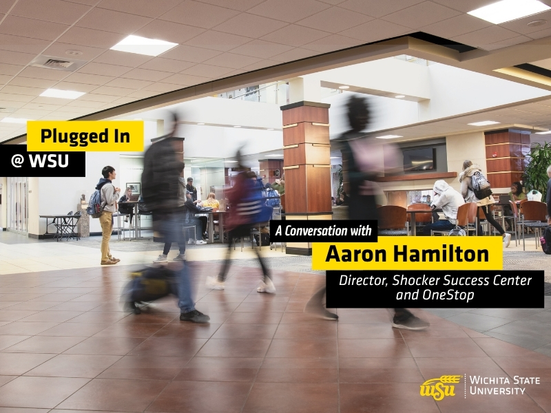 Students walk through a busy indoor campus commons area at Wichita State University. Several people are shown moving across the foreground with motion blur, while others sit and study at tables in the background. Overlay text reads "Plugged In @ WSU" and "A Conversation with Aaron Hamilton, Director, Shocker Success Center and OneStop." The Wichita State University logo appears in the lower-right corner. The image promotes a podcast episode featuring WSU Success Coaches and highlights student activity and engagement on campus.