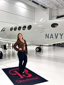 Student standing in front plane in hanger.