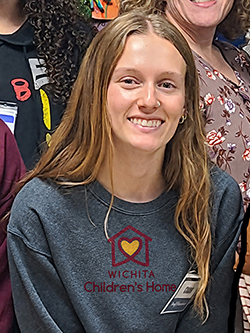 Girl posing for picture with a t-shirt reading "Wichita Children's Home."