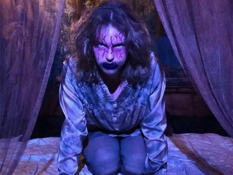 A student in Halloween makeup crawls up to the camera