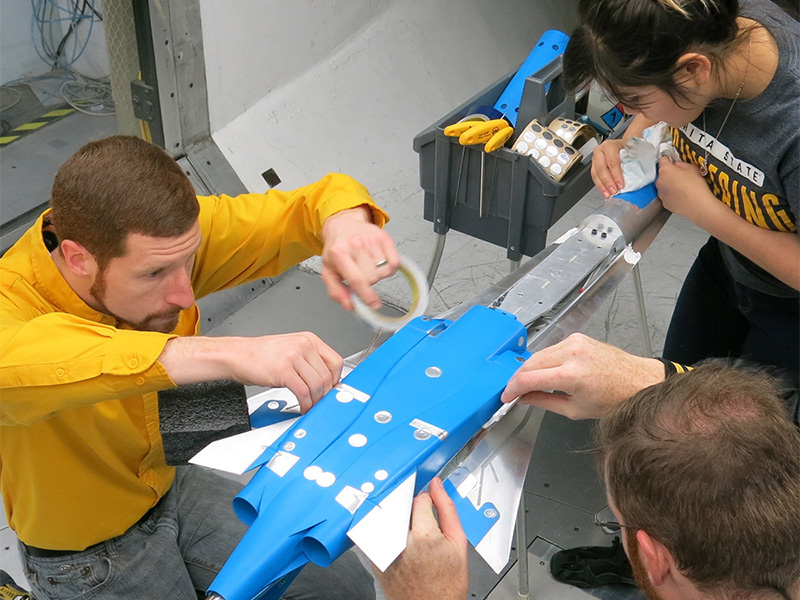 Kevin Kelly works on test model of a plane alongside students