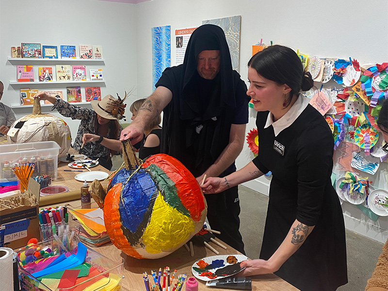 Girl painting paper mache pumpkin pinata